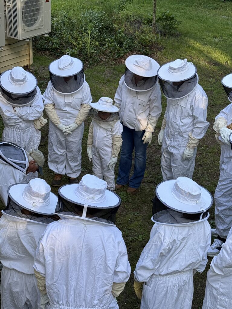 Intro to Beekeeping event. Students in bee suits watching the professor.