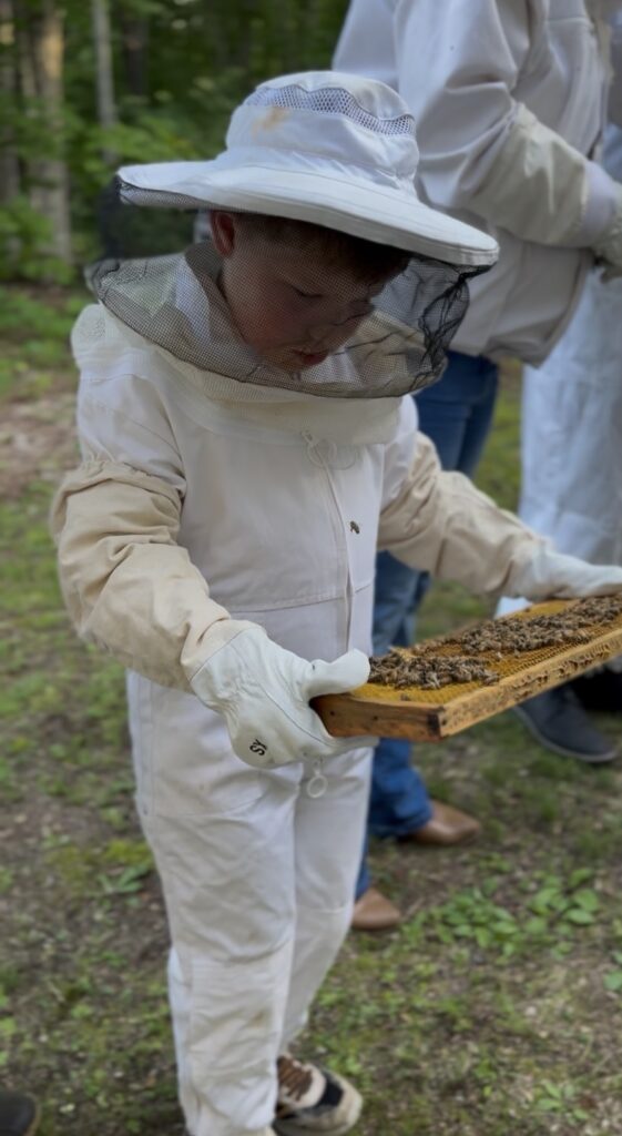 Intro to Beekeeping class. Young student handling hive.